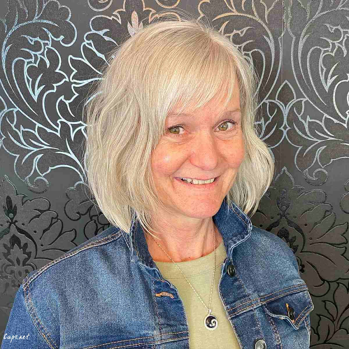 stylish blonde layered bob with wispy bangs for 60 year olds