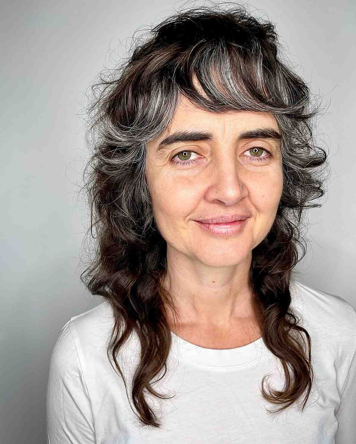 medium length curly shag with bangs for women over 60 with dark hair