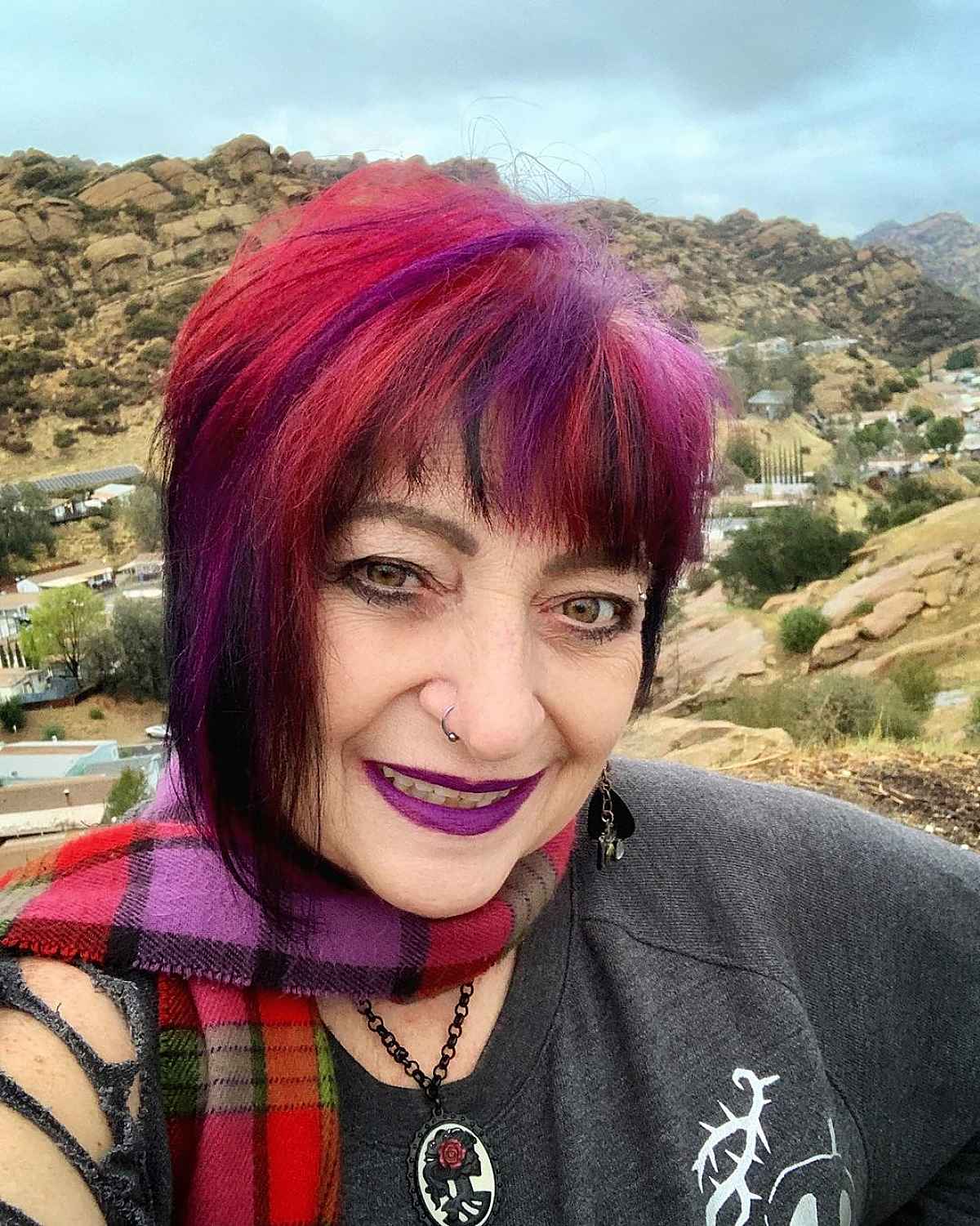 woman over 60 with a very edgy pink purple and red haircut and bangs